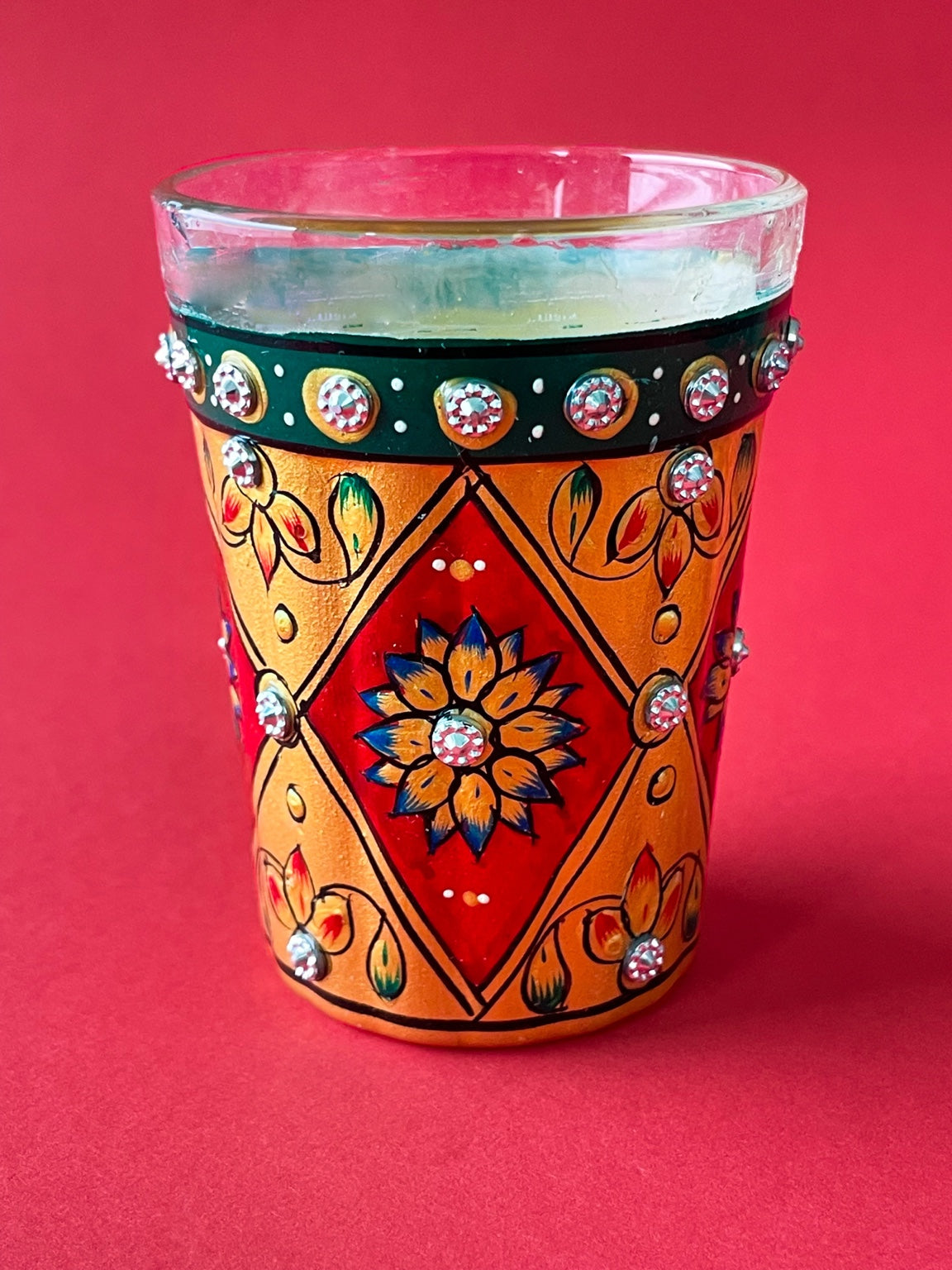A filled hand-painted chai glass used in a Ghar Ki Chai tasting scene
