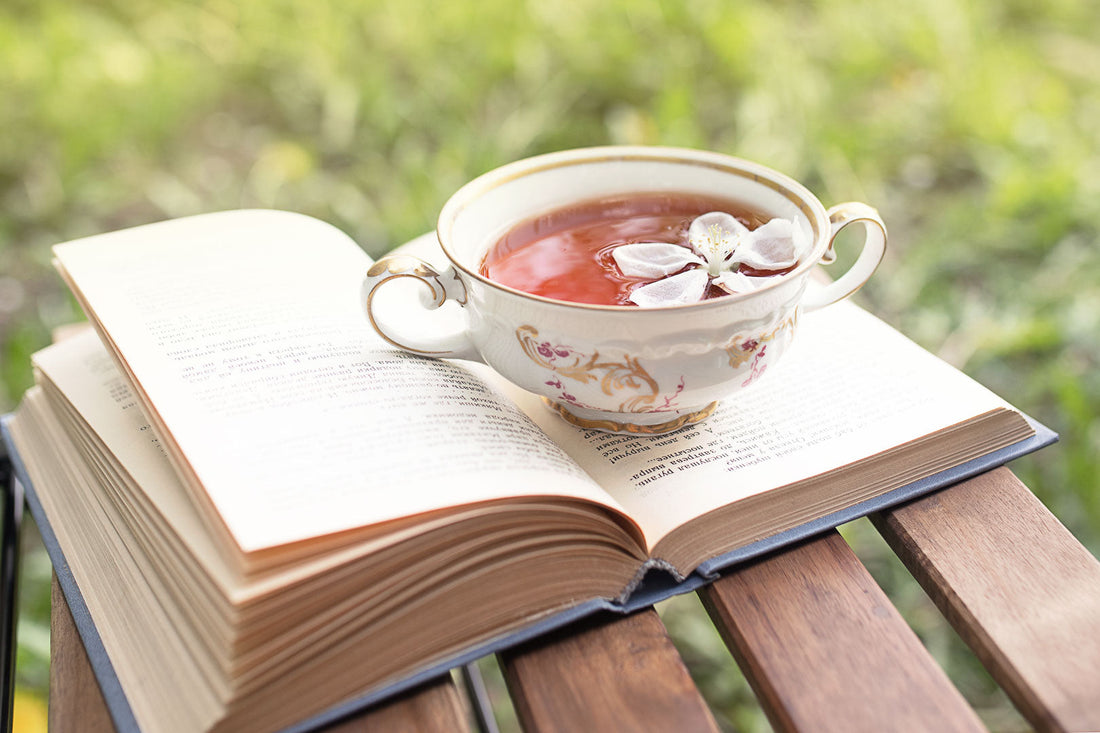 Tea resting on an open book outdoors in warm summer light
